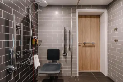 a bathroom with a shower with a chair in it at Holiday Inn Express Liverpool - Central by IHG in Liverpool