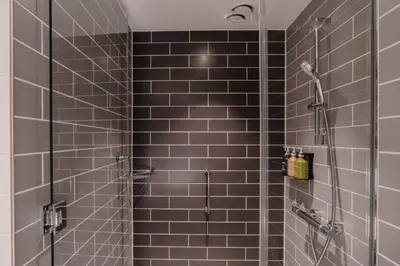 a bathroom with a shower with brown tiles at Holiday Inn Express Liverpool - Central by IHG in Liverpool