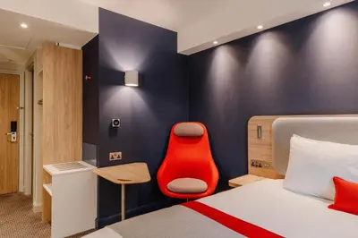 a hotel room with a bed and a red chair at Holiday Inn Express Liverpool - Central by IHG in Liverpool