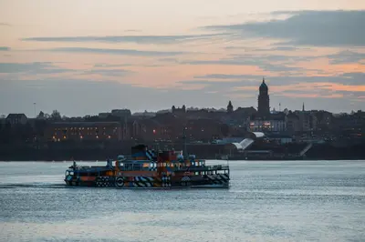 a boat on the water with a city in the background at The Halyard Liverpool, Vignette Collection by IHG in Liverpool