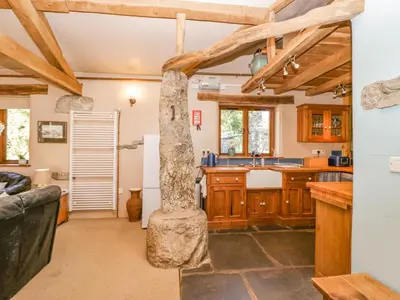 a kitchen with wooden cabinets and a stone pillar at Egg Pudding Stone in Grange Over Sands