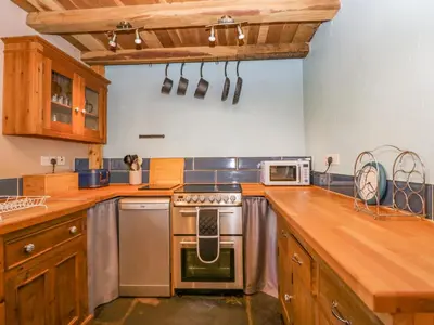 a kitchen with wooden cabinets and a stove top oven at Egg Pudding Stone in Grange Over Sands