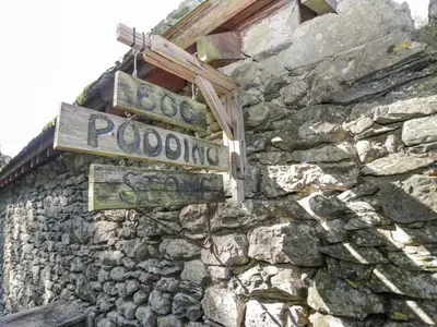 a stone wall with street signs on it at Egg Pudding Stone in Grange Over Sands