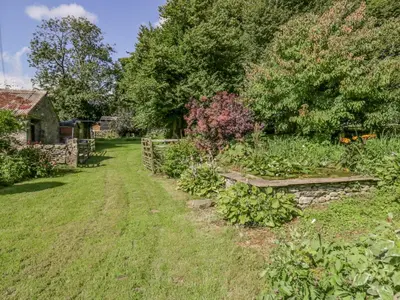 a garden with a bench and a stone wall at Egg Pudding Stone in Grange Over Sands