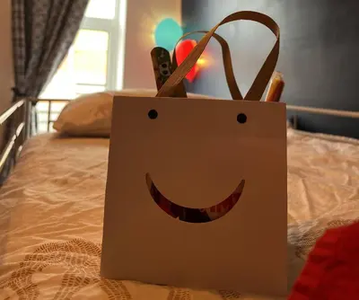 a shopping bag with a smiley face on a bed at Emerald Apartment Pleasure Beach Blackpool in Blackpool