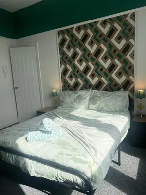 a bedroom with a bed with a wooden headboard at Emerald Apartment Pleasure Beach Blackpool in Blackpool