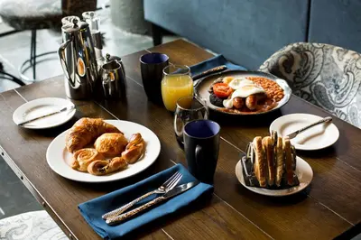 a table topped with plates of breakfast foods and orange juice at Titanic Hotel Liverpool in Liverpool