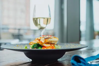 a plate of food on a table with a glass of wine at Titanic Hotel Liverpool in Liverpool