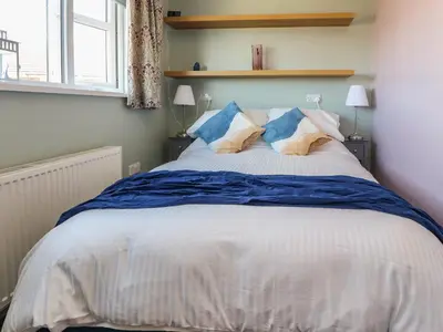a bedroom with a large bed with blue and white sheets at 26 North Promenade in Cleveleys