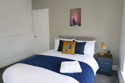 a bedroom with a large white bed with a blue blanket at Ideal Base for Contractors in Central Morecambe- 3 Double Bedrooms in Morecambe