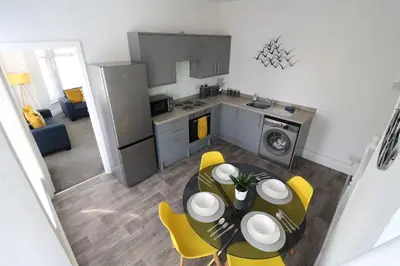 a kitchen and dining room with a table and yellow chairs at Ideal Base for Contractors in Central Morecambe- 3 Double Bedrooms in Morecambe