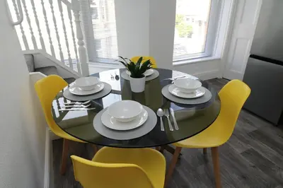 a dining room table with yellow chairs and a black table at Ideal Base for Contractors in Central Morecambe- 3 Double Bedrooms in Morecambe