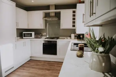 a kitchen with white cabinets and a counter with flowers at Pattys Barn Holiday Cottages, Cabins and Venue Hire in Cockerham