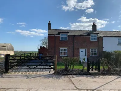 a brick house with a gate in front of it at Newton Hall Farm cottage, hot tub garden views Nr Lytham Ribby in Preston