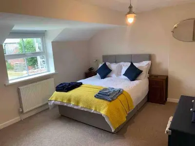 a bedroom with a bed with a yellow and blue blanket at Newton Hall Farm cottage, hot tub garden views Nr Lytham Ribby in Preston