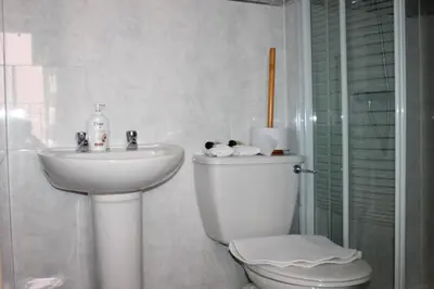 a white bathroom with a toilet and a sink at Brecks Hotel in Blackpool