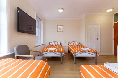 a room with three beds and a flat screen tv at Brecks Hotel in Blackpool