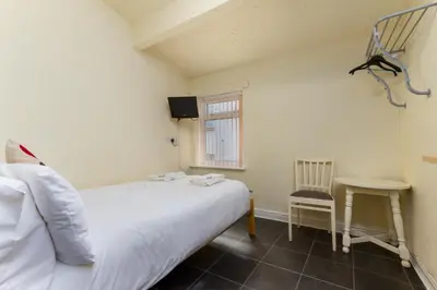 a bedroom with a bed and a table and a chair at Brecks Hotel in Blackpool