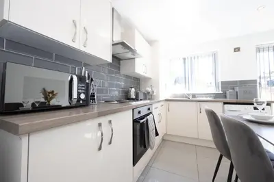a kitchen with white cabinets and a counter with a microwave at Contemporary 3 Bedroom Home with Garden & Parking in Atherton