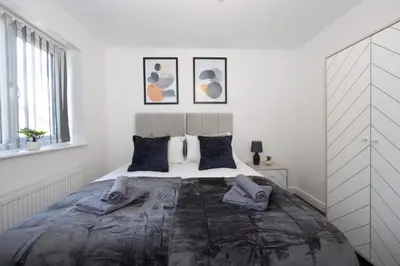 a white bedroom with a large bed with two pillows at Contemporary 3 Bedroom Home with Garden & Parking in Atherton