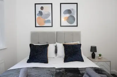 a bedroom with a bed with four pictures on the wall at Contemporary 3 Bedroom Home with Garden & Parking in Atherton