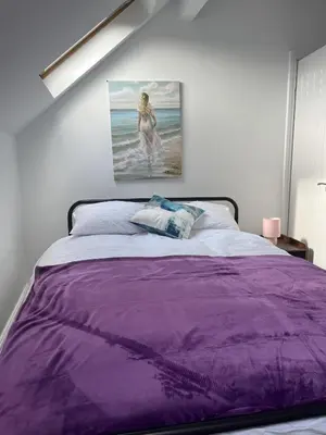 a bedroom with a purple bed with a painting on the wall at Moorside House in Bolton