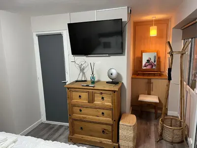 a bedroom with a dresser and a tv on a wall at Happy days Moreton , 2 miles from Hoylake Wirral in Moreton