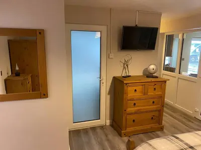 a bedroom with a dresser and a sliding glass door at Happy days Moreton , 2 miles from Hoylake Wirral in Moreton