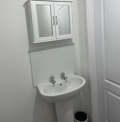 a white bathroom with a sink and a cabinet at Buckshaw Snoozy in Heapey