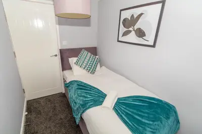 a bedroom with a bed with a green blanket on it at Bloomfield Apartments in Blackpool