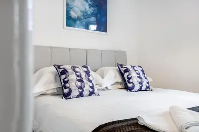 a bed with blue and white pillows on it at Bloomfield Apartments in Blackpool