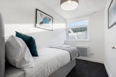a white bedroom with a bed and a window at Bloomfield Apartments in Blackpool