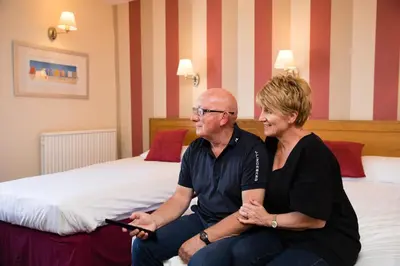 a man and a woman sitting on a bed at Claremont Hotel - All Inclusive! in Blackpool