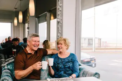 a man and a woman sitting in a chair with cups at Claremont Hotel - All Inclusive! in Blackpool
