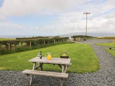 a picnic table with drinks and a basket on it at Orchard in Dalton in Furness