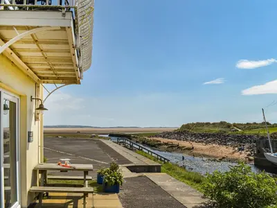 a porch with a picnic table and a view of the beach at Kingfishers Rest in Millom