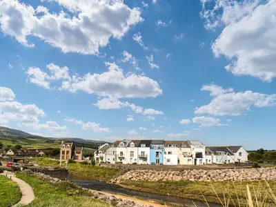 a group of houses on a hill next to a river at Kingfishers Rest in Millom