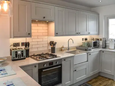 a kitchen with white cabinets and a sink at Kingfishers Rest in Millom
