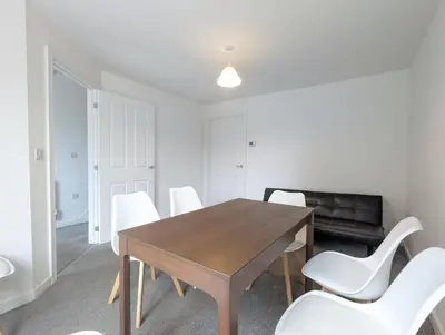 a dining room with a wooden table and white chairs at Guest Rooms Near City Centre & Anfield Free Parki in Liverpool