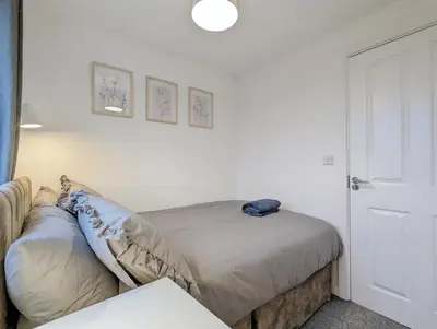 a bedroom with a bed and a white wall at Guest Rooms Near City Centre & Anfield Free Parki in Liverpool