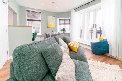a living room with a green couch and windows at Clock Tower Retreat - Sea View Apartments in Morecambe in Morecambe