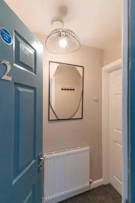 a hallway with a mirror and a blue door at Clock Tower Retreat - Sea View Apartments in Morecambe in Morecambe