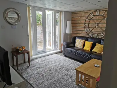 a living room with a couch and a large window at Private garden apartment with secure parking in Southport