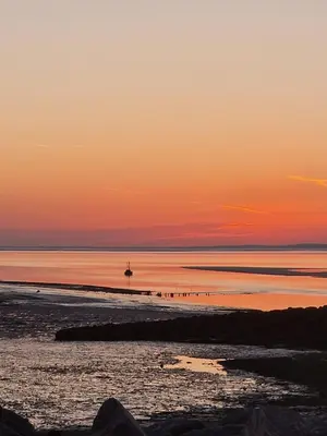 a beach at sunset with a boat in the water at Fylde Court in Morecambe