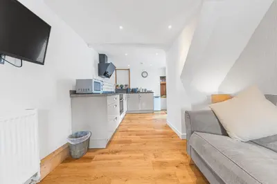 a living room with a couch and a kitchen at The Black Dog Apartment in Dalton in Furness