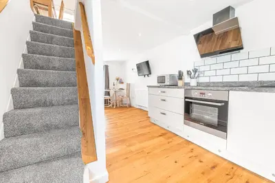a kitchen with a staircase and a living room at The Black Dog Apartment in Dalton in Furness