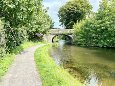 a bridge over a river next to a path at A modern, dog-friendly 3 bedrm canal side property in Bolton le Sands