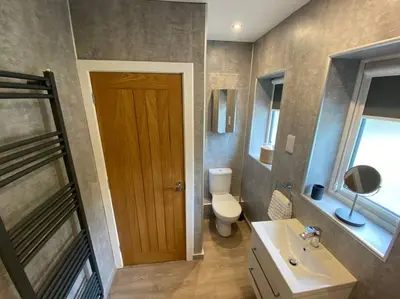 a bathroom with a toilet and a sink and a door at A modern, dog-friendly 3 bedrm canal side property in Bolton le Sands