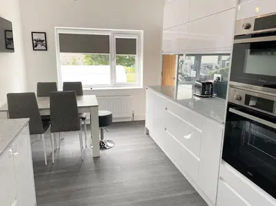 a kitchen with white cabinets and a table with chairs at A modern, dog-friendly 3 bedrm canal side property in Bolton le Sands