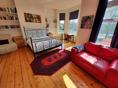 a living room with a red couch and a bed at Anfield Haven in Liverpool